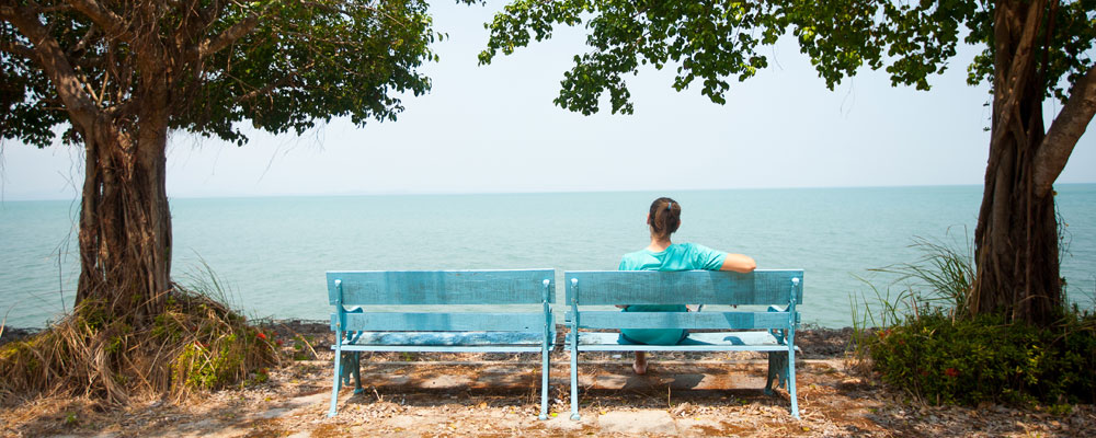 woman sitting on a bench overlooking the ocean