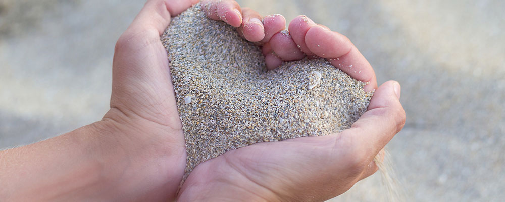 Hands holding sand in shape of heart